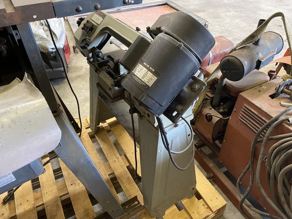 A metal band saw is sitting on top of a wooden pallet.
