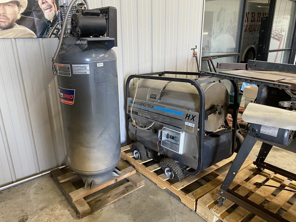 A pressure washer is sitting on a wooden pallet next to an air compressor.