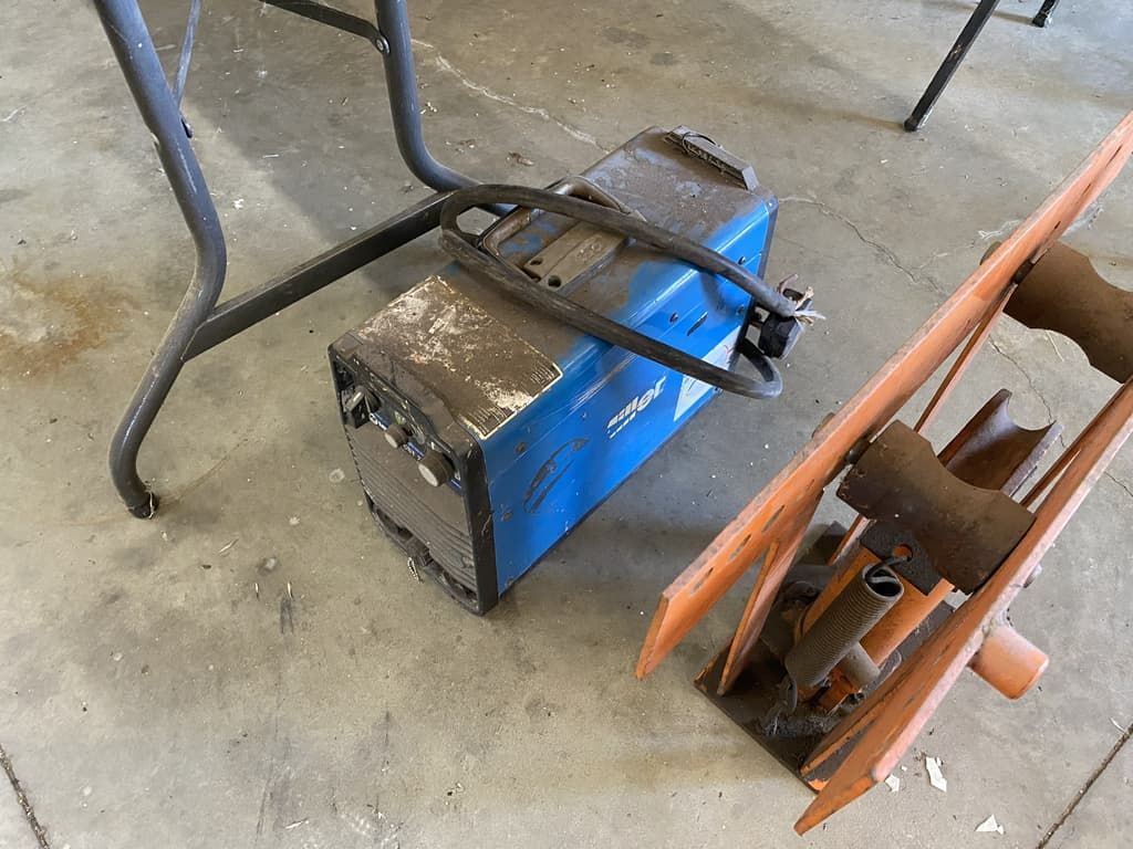 A welding machine is sitting on the ground next to a table.