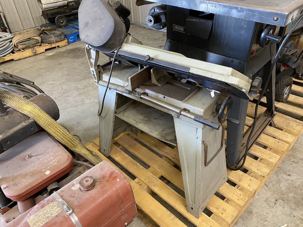A table saw is sitting on top of a wooden pallet in a garage.