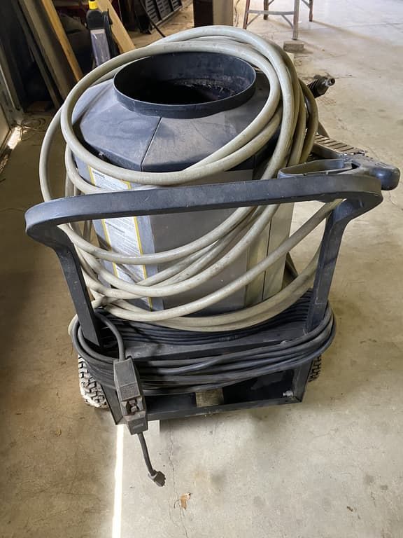 A vacuum cleaner with a hose attached to it is sitting on the floor.