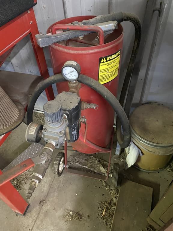 A red sandblasting machine is sitting on a table in a garage.