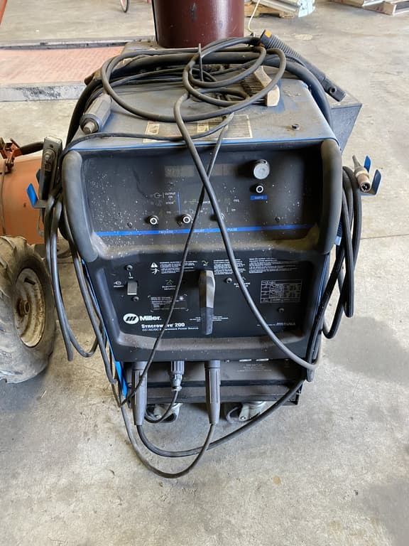 A welding machine is sitting on a concrete floor in a garage.