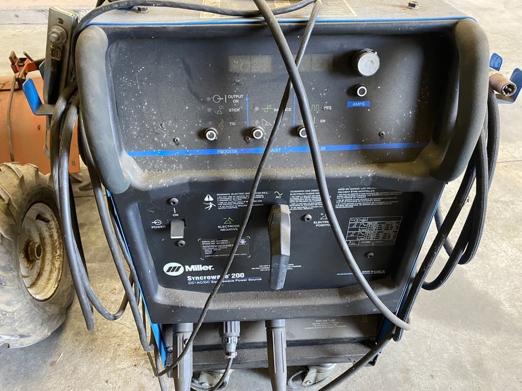 A welding machine is sitting on the ground in a garage.