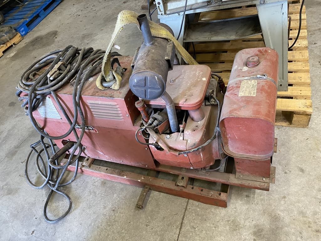 A red machine is sitting on top of a wooden pallet in a garage.