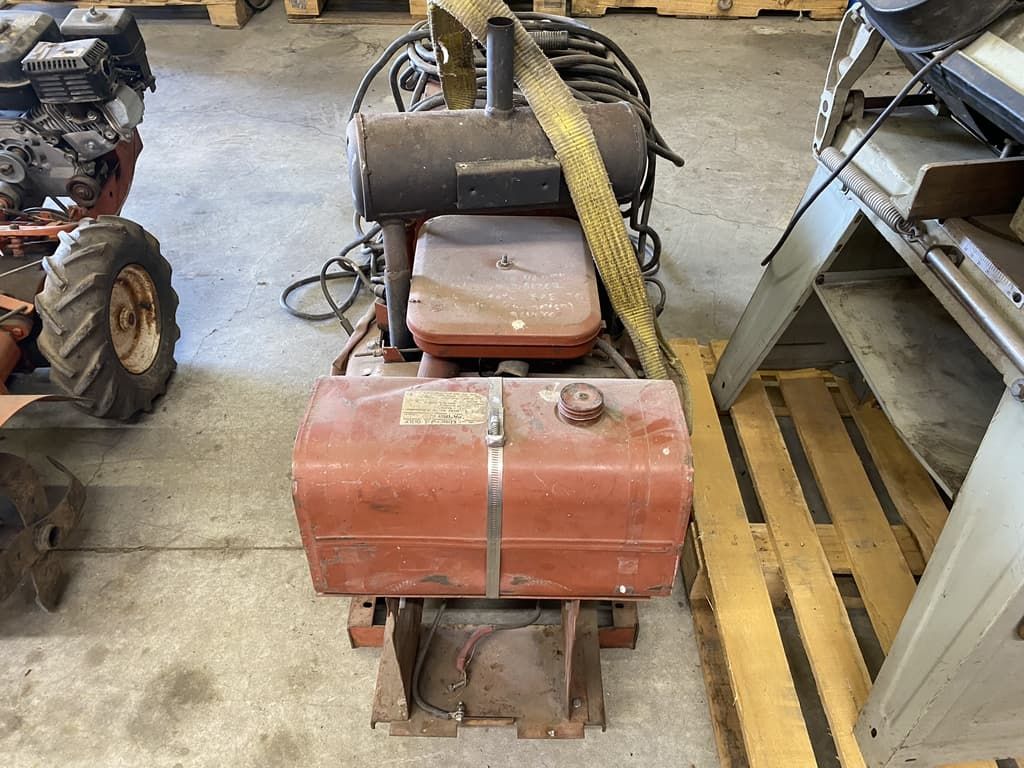A red tank is sitting on top of a wooden pallet in a garage.
