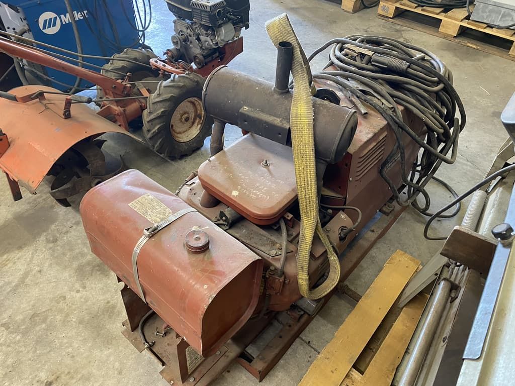 A machine is sitting on a pallet in a garage next to a tractor.