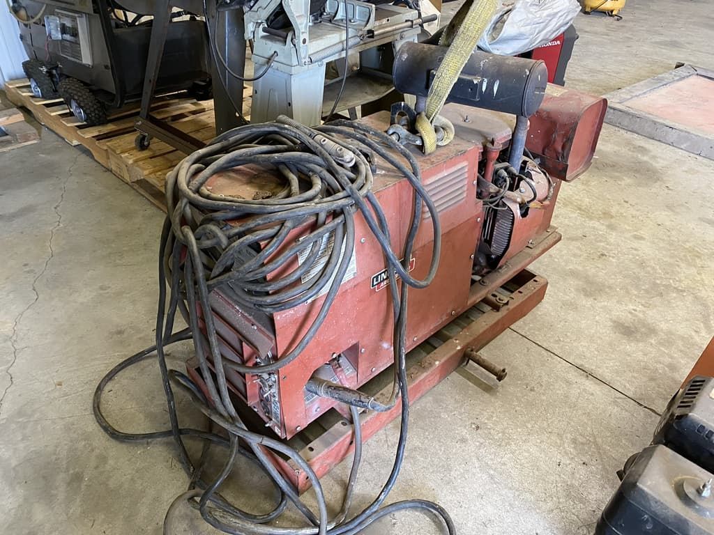 A machine with a lot of wires attached to it is sitting on a pallet in a garage.