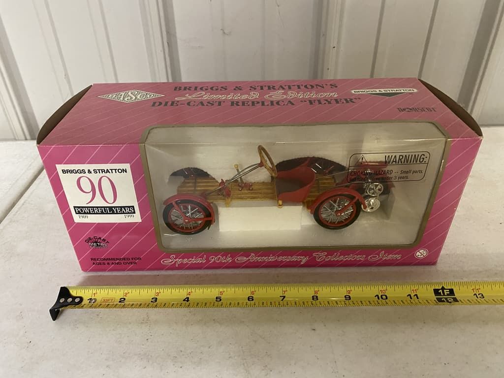 A toy car in a pink box with a tape measure next to it.