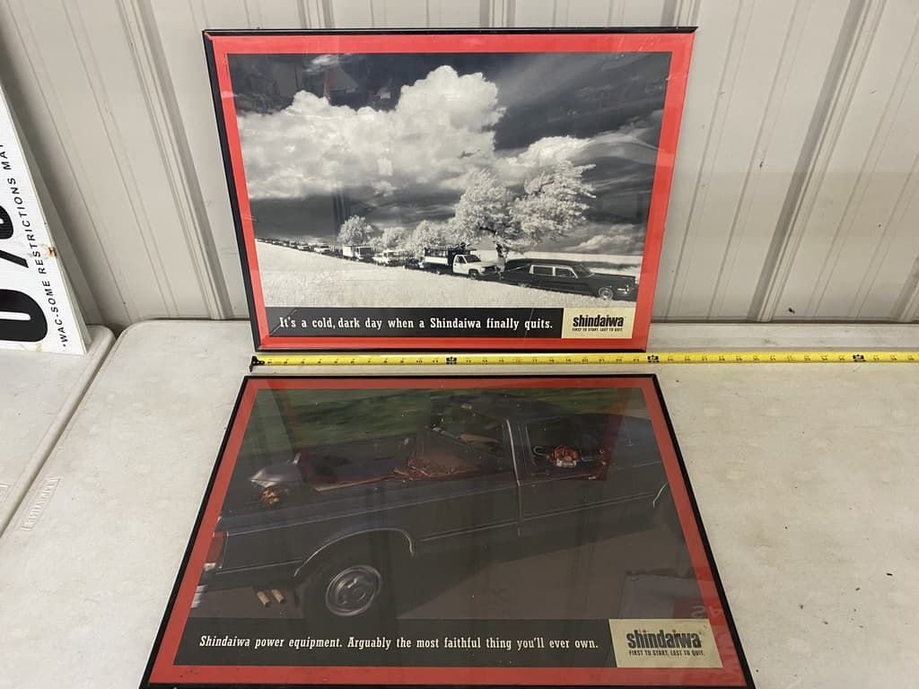 Two framed pictures of cars are sitting on a table.