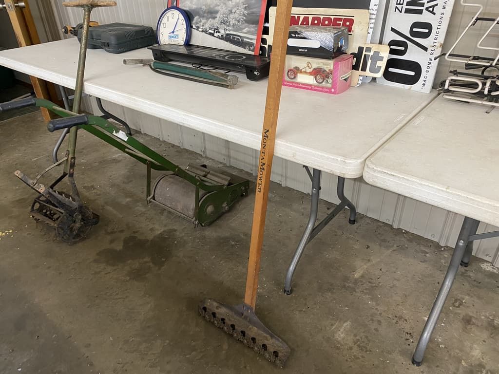 A broom is sitting on a table next to a lawn mower.