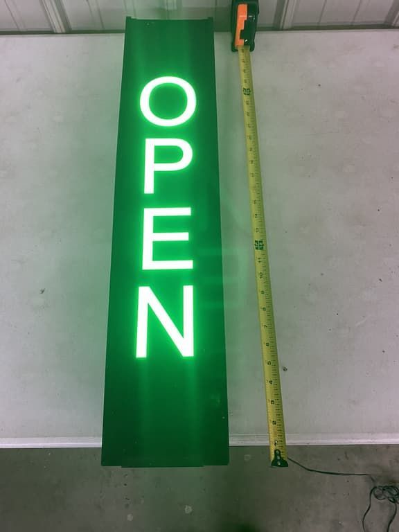 A green sign that says open next to a tape measure