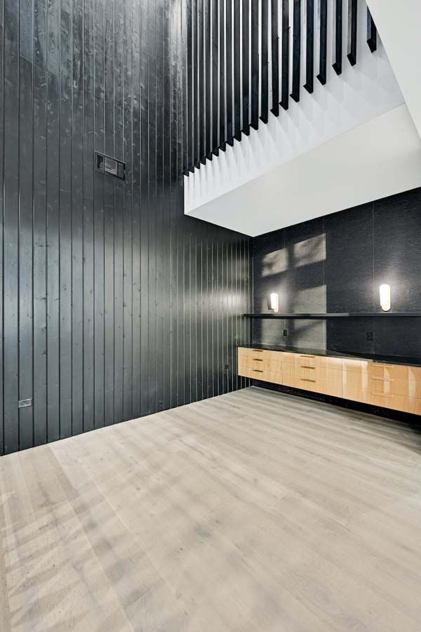 An empty room with a wooden floor and black walls.