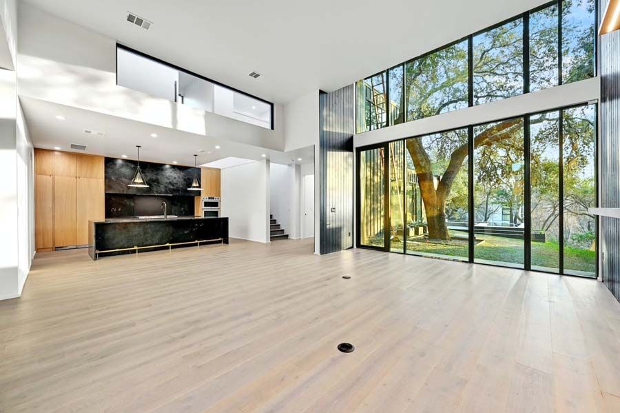 A large empty room with a kitchen and a lot of windows.