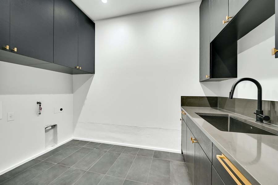 An empty kitchen with black cabinets and a sink.