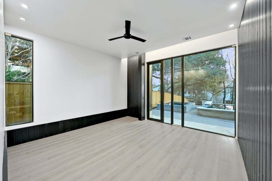 An empty living room with a ceiling fan and sliding glass doors.