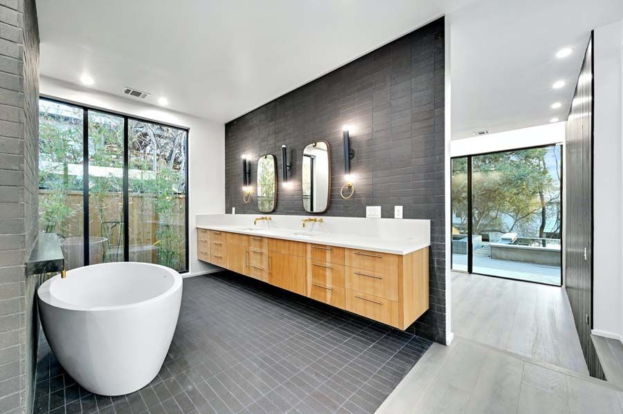 A bathroom with a bathtub , sinks , mirrors and a large window.