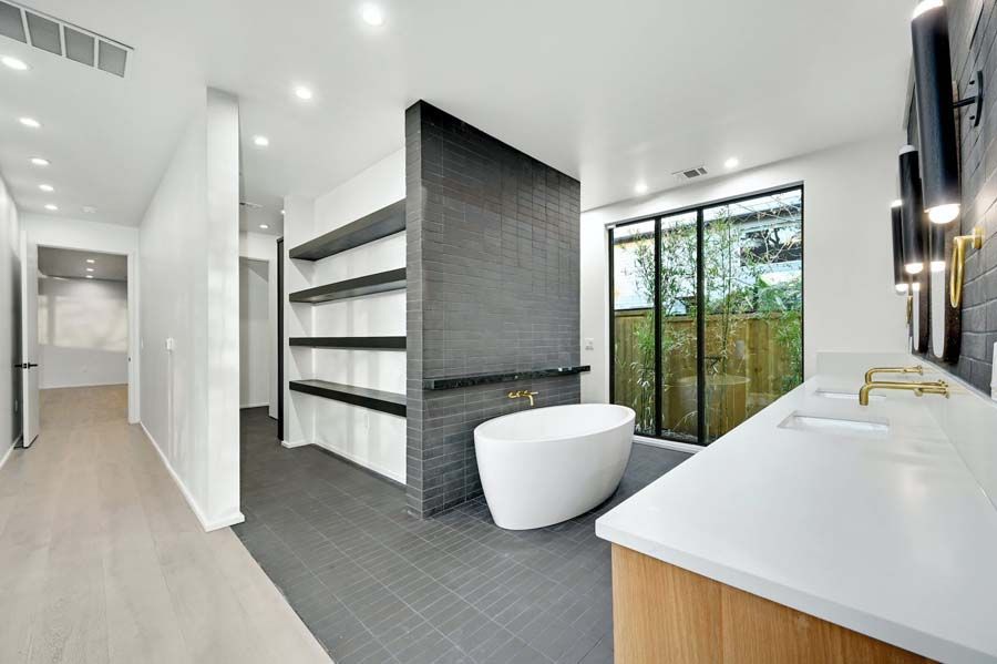 A bathroom with a bathtub , sinks , and shelves.