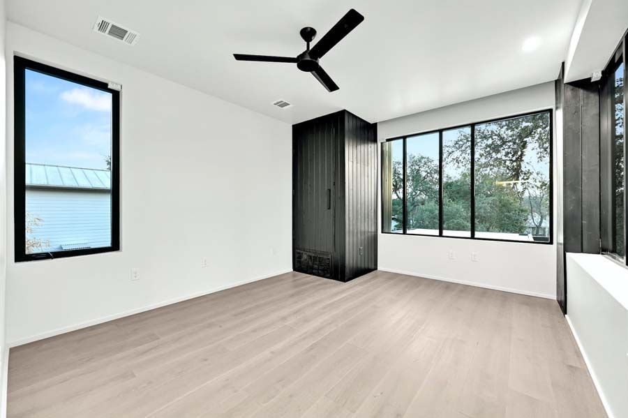 A large empty room with a ceiling fan and lots of windows.