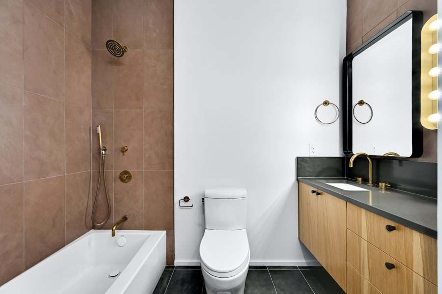 A bathroom with a toilet , tub , sink and mirror.