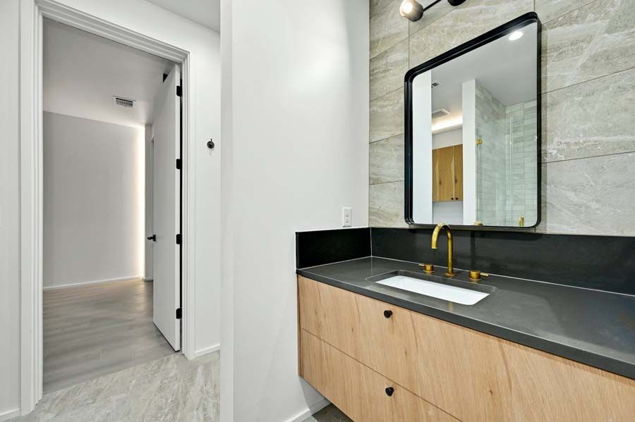 A bathroom with a sink , mirror and wooden cabinets.