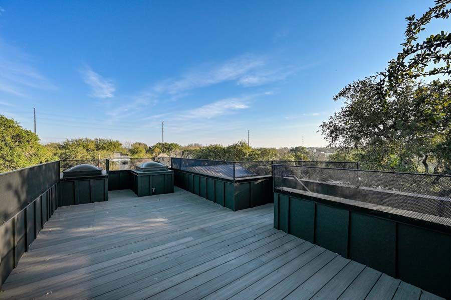 A large wooden deck with a view of a city and trees.