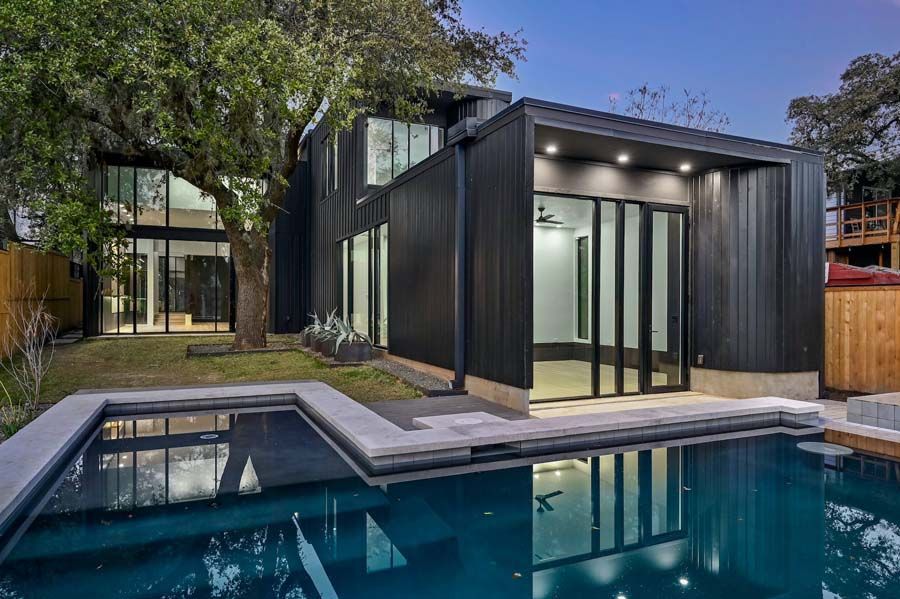 A modern house with a large swimming pool in front of it.