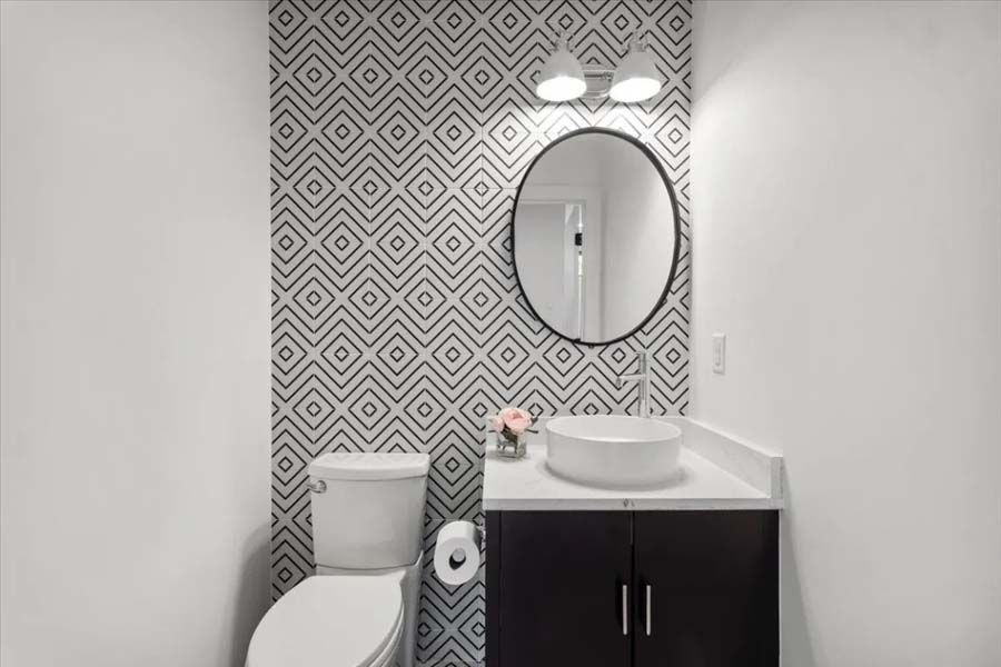 A bathroom with a toilet , sink and mirror.
