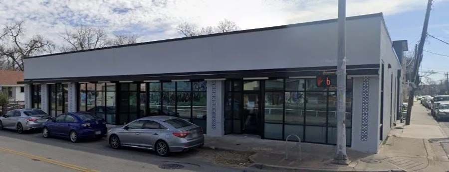 A building with a lot of windows and cars parked in front of it.