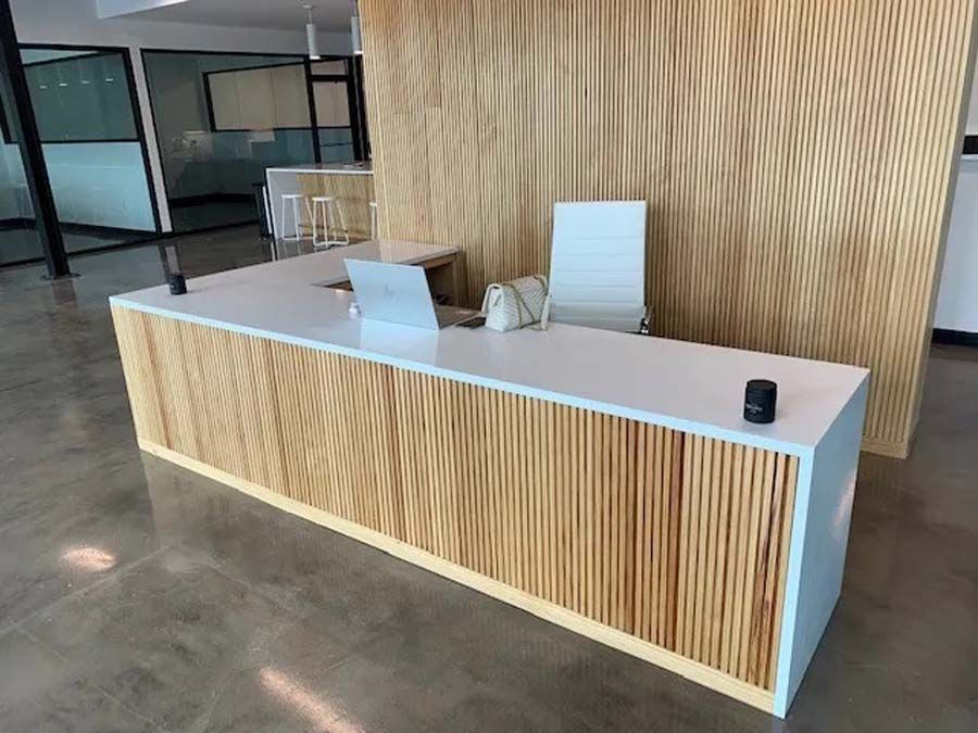 A long wooden reception desk with a laptop on top of it.