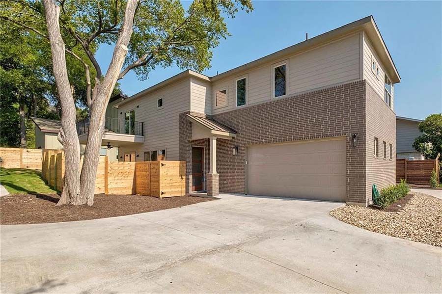 A large house with a concrete driveway and a fence in front of it.