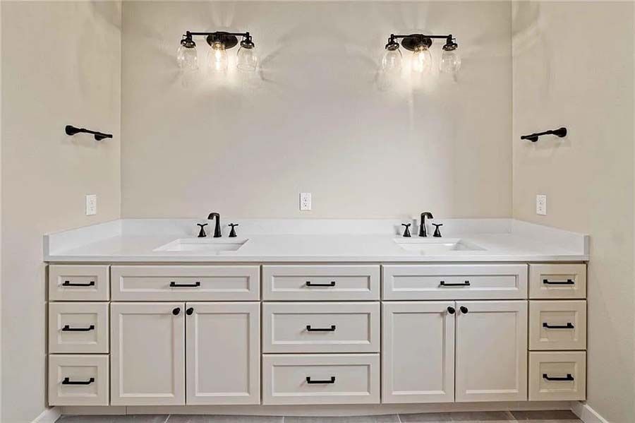 A bathroom with two sinks and two lights on the wall.