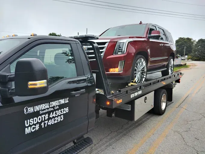 A red SUV being towed by a black tow truck on a road.
