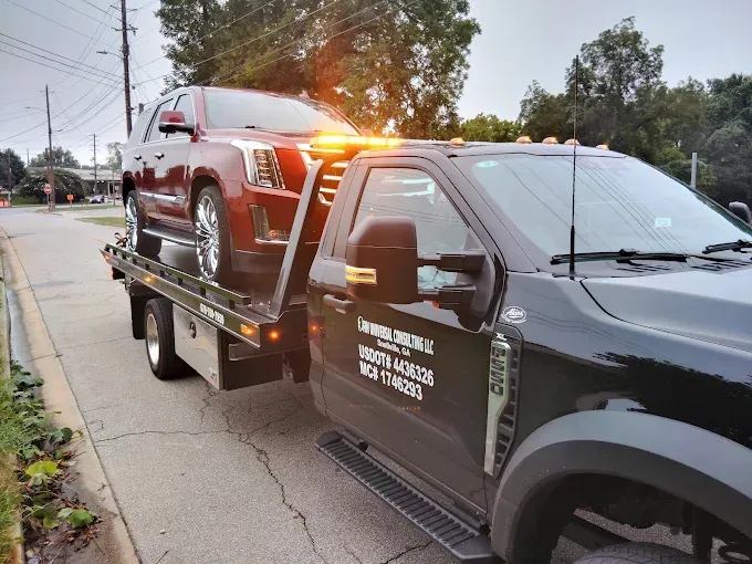 Red SUV loaded on a black tow truck, parked on a street.