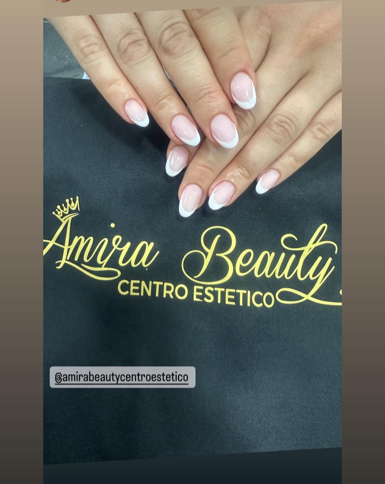 Le unghie di una donna sono esposte davanti al logo di amira beauty centro estetico