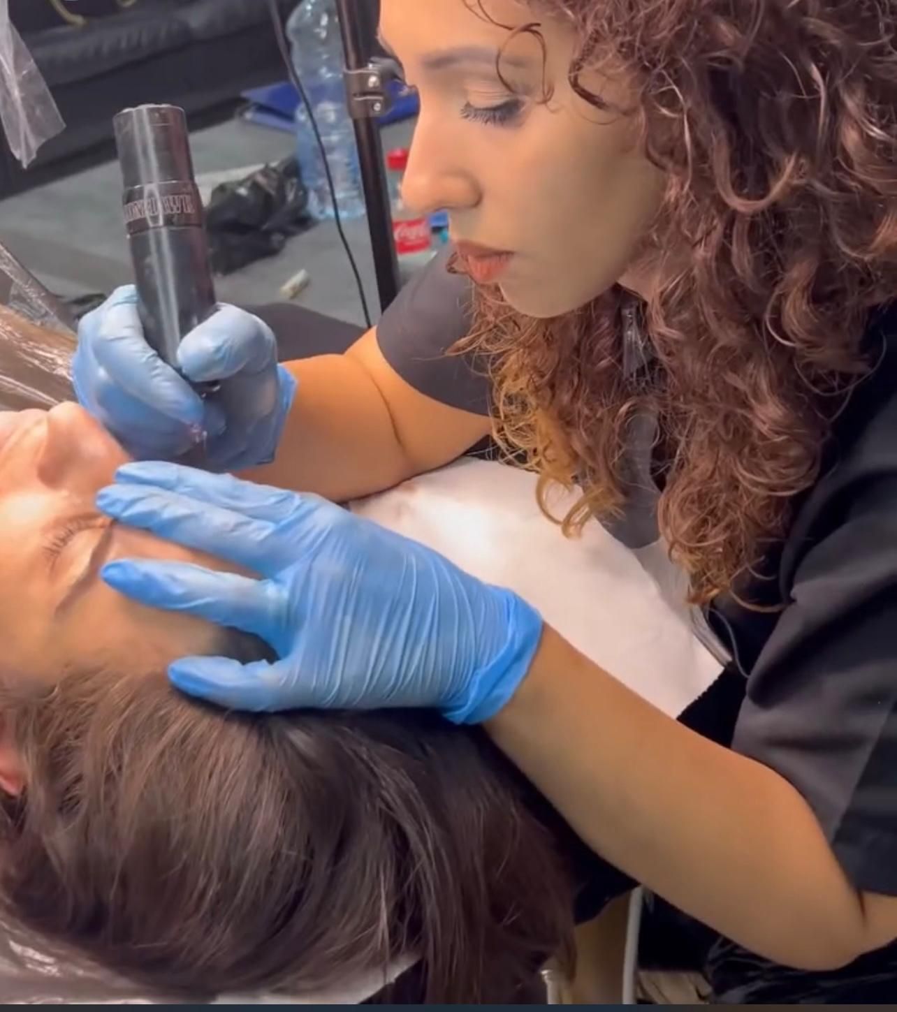 Una donna che indossa guanti blu sta applicando il trucco sul viso di una donna