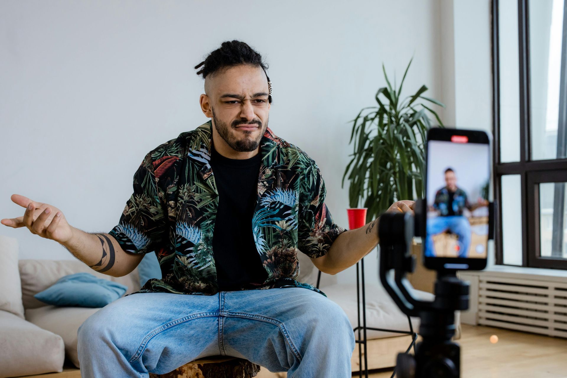 A man is sitting on a drum recording himself on a camera.