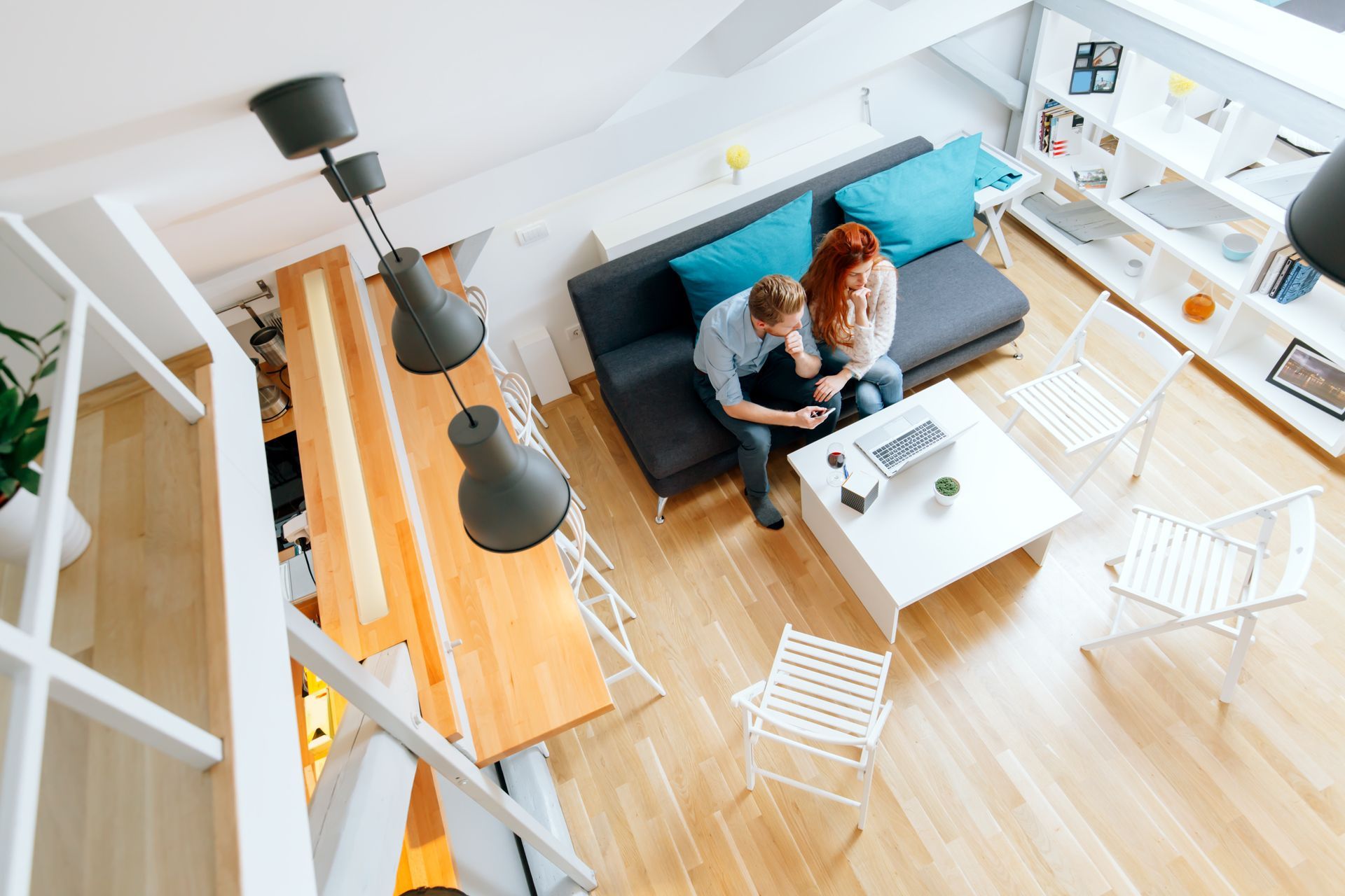 A man and a woman are sitting on a couch in a living room surrounded by cardboard boxes.