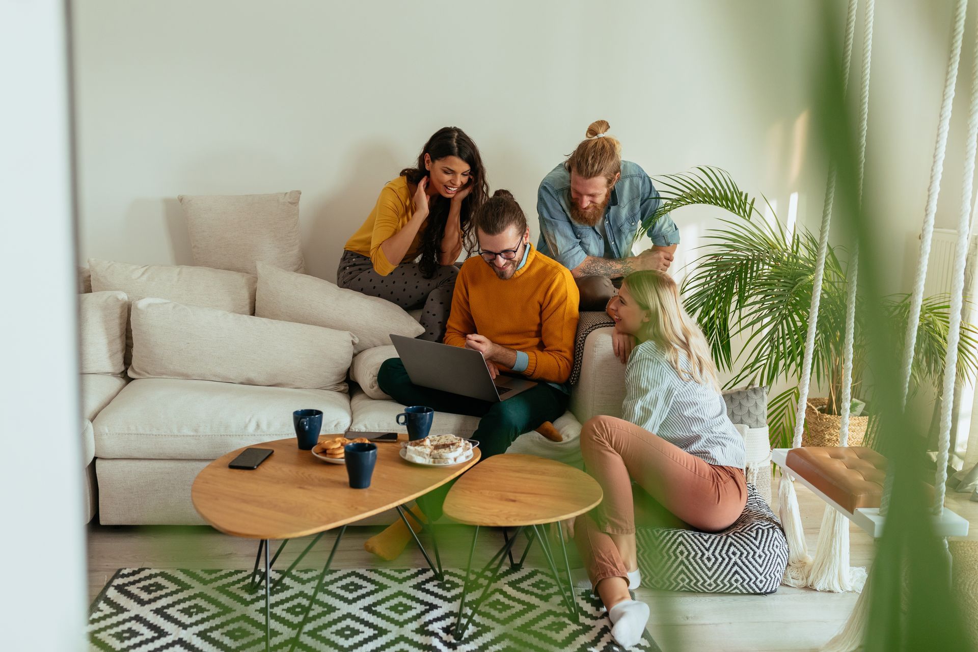 A group of people are sitting on a couch looking at a laptop.