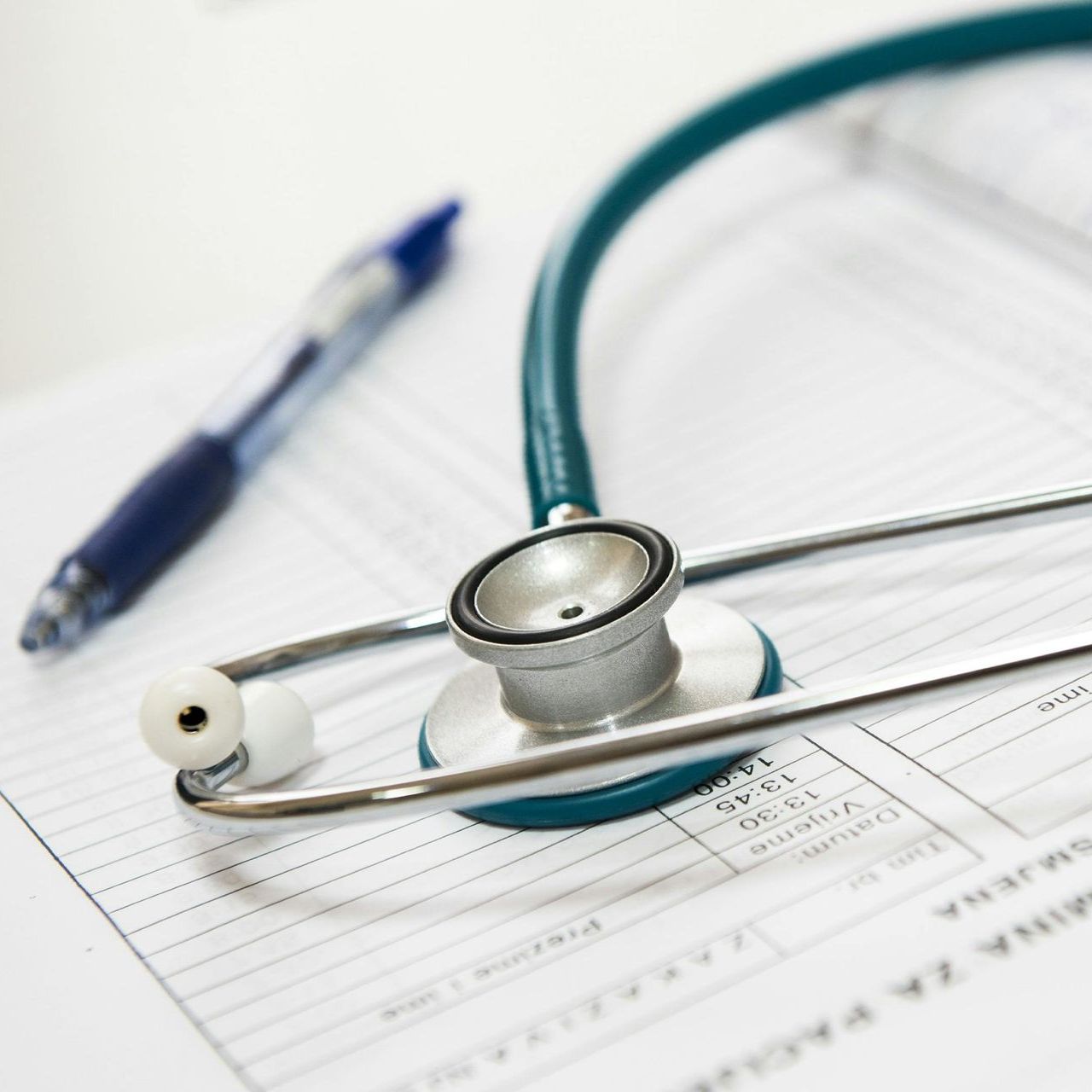 A stethoscope is laying on a piece of paper next to a pen