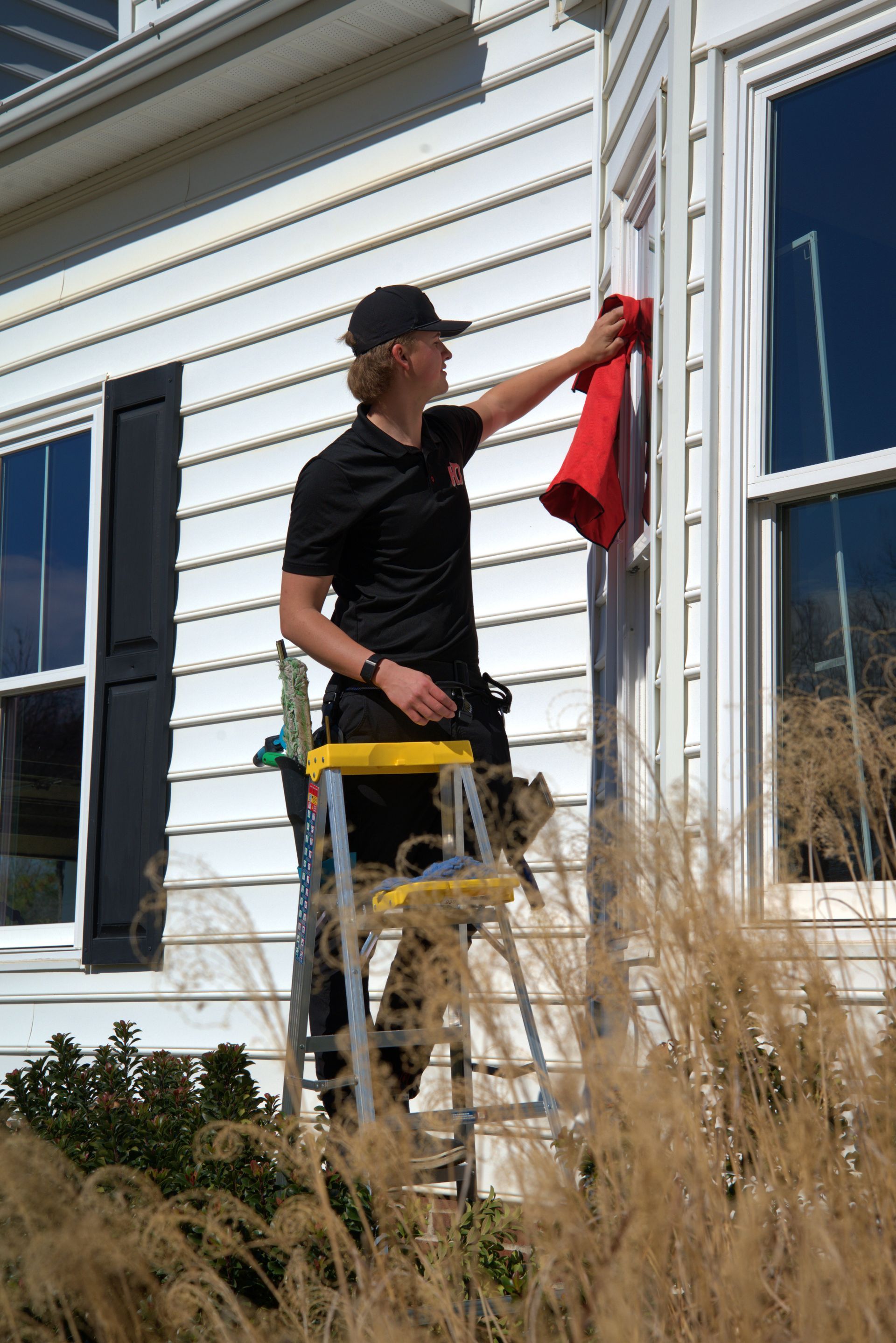 Person cleaning a window with a squeegee; house exterior in the background.