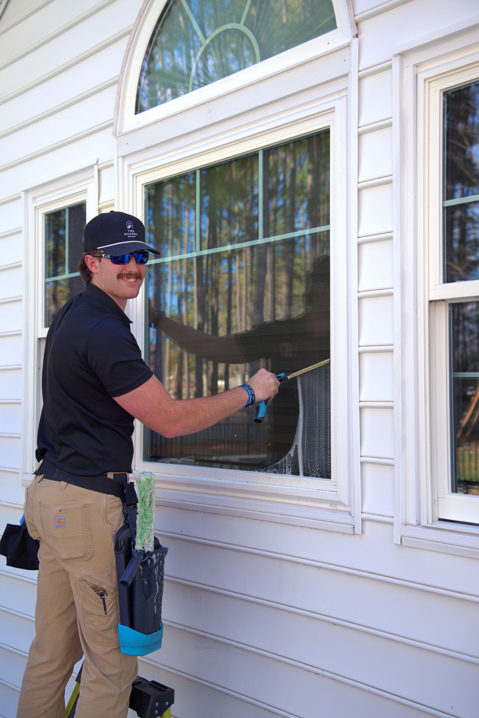 Man cleaning a window with a squeegee on a house's exterior.