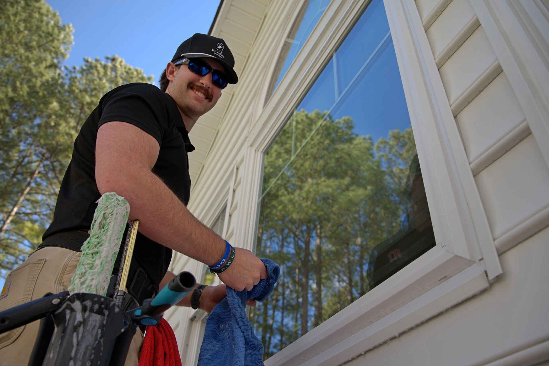 Person wiping a window, standing in front of a red building with a red awning.