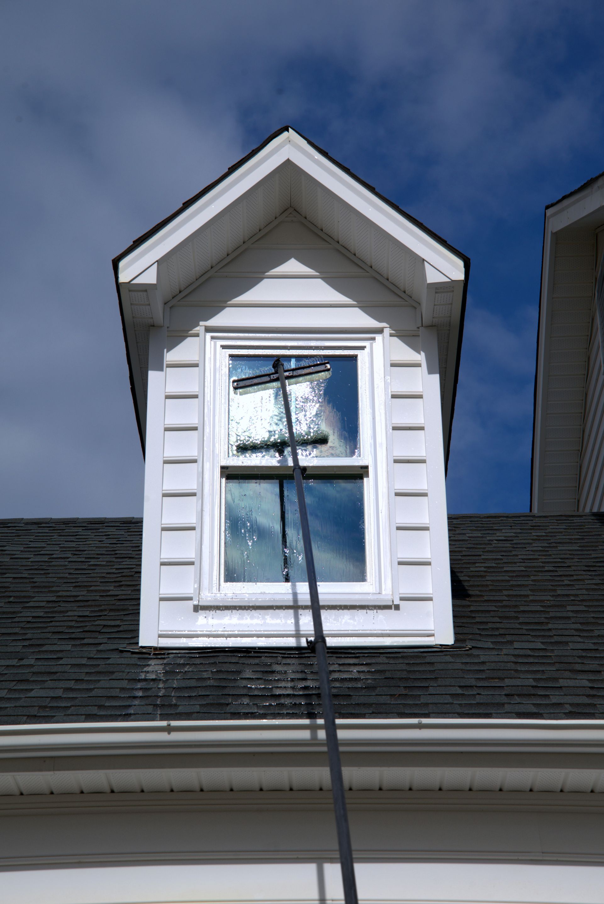 A person stands outside, operating a large bubble machine, with a hose in hand.