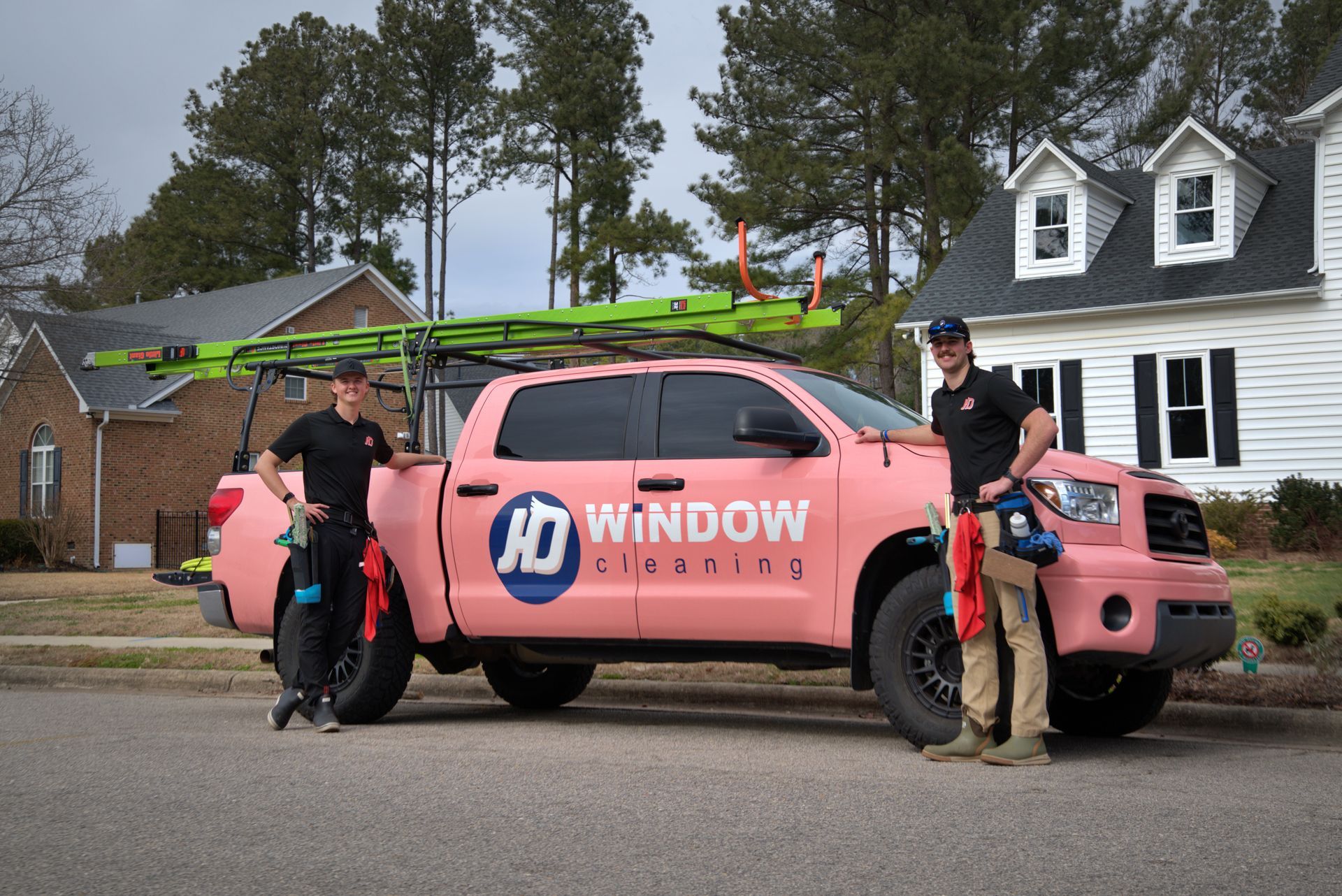 Two men stand beside a pink truck with 