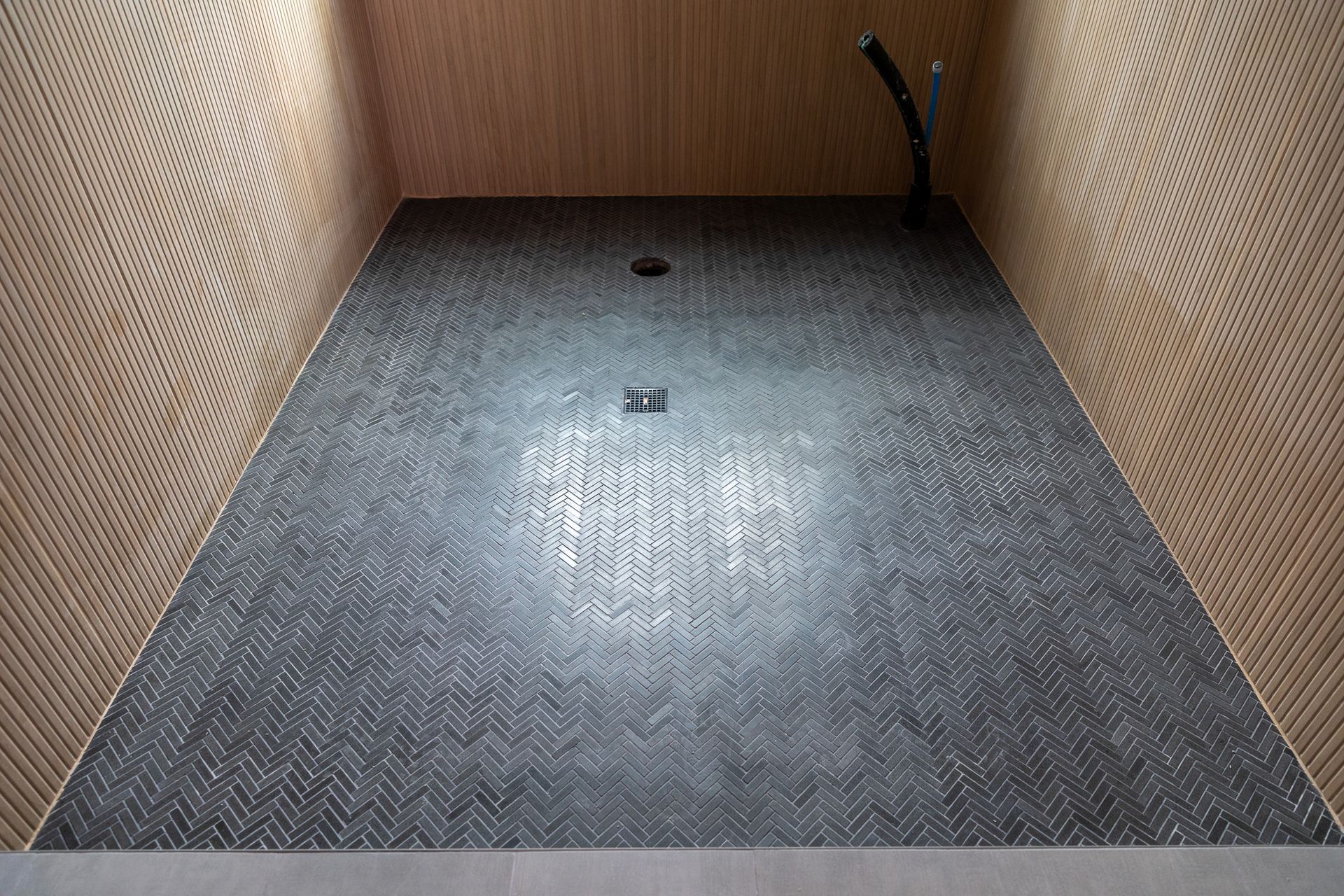 A bathroom with a black tiled floor and a shower head.
