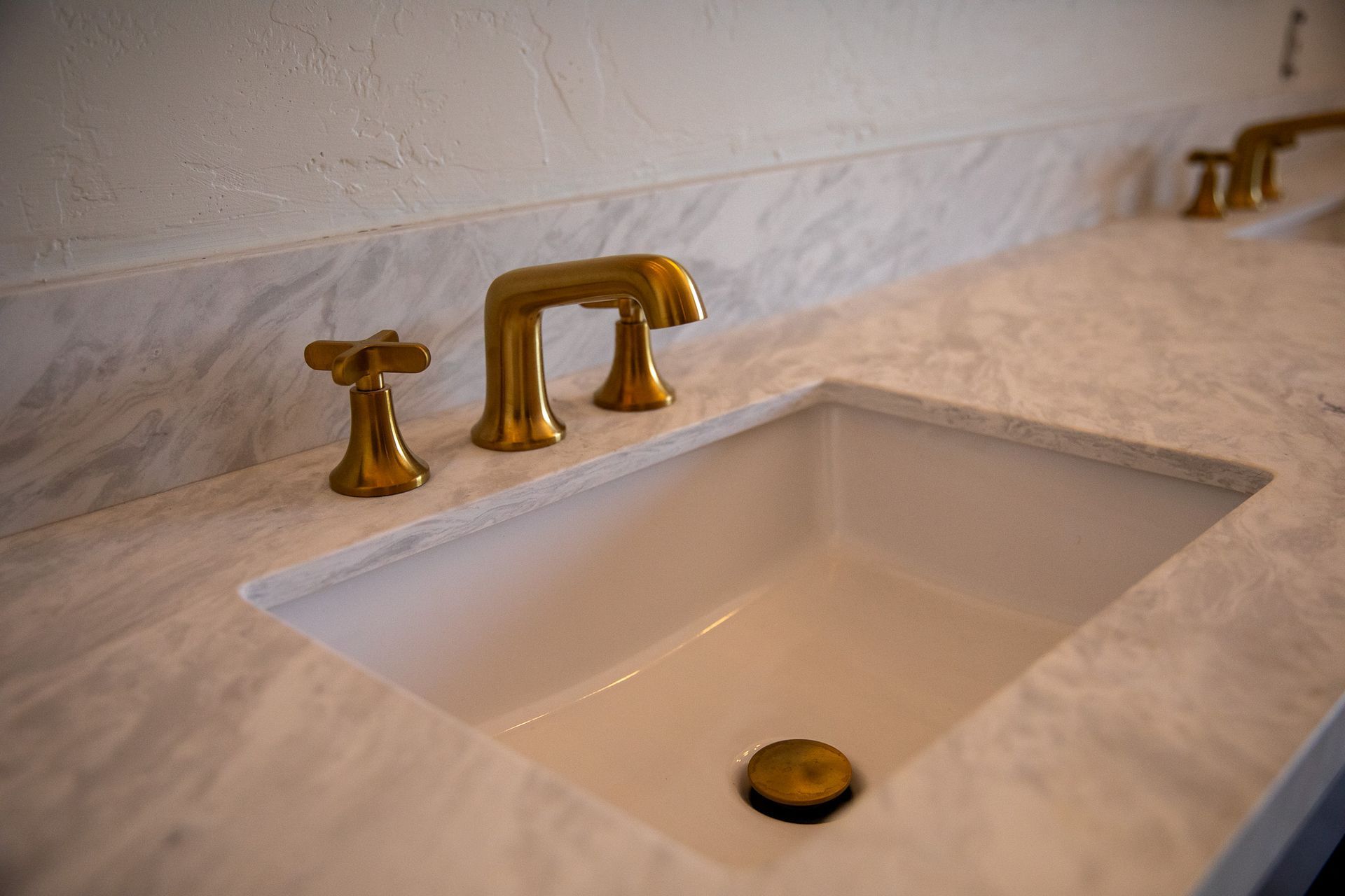 A bathroom sink with gold faucets on a marble counter top.