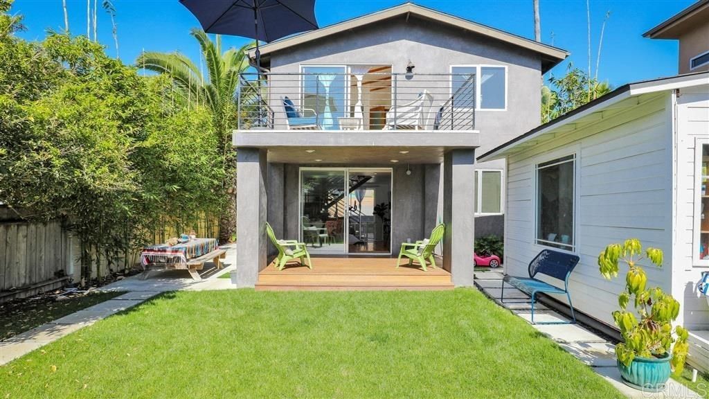 The back of a house with a large lawn and a balcony.