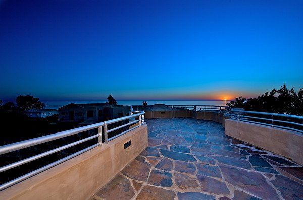 A balcony with a view of the ocean at sunset.