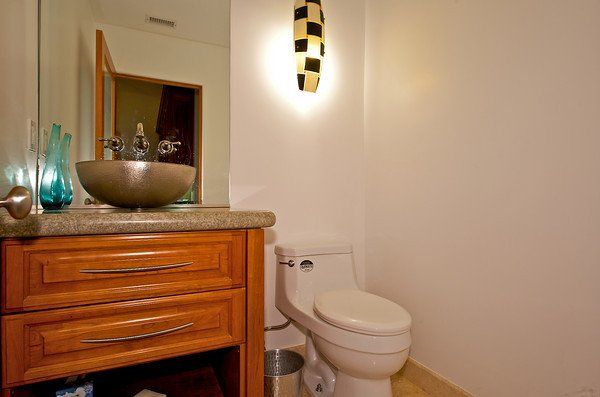 A bathroom with a toilet , sink and mirror.
